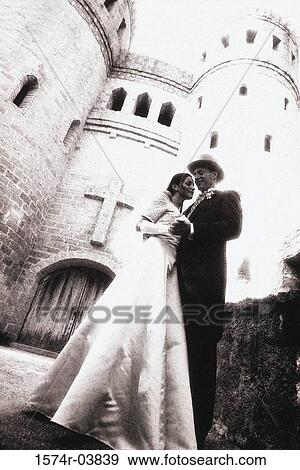 Low angle view of a newlywed couple standing outside of a castle View Large Photo Image Stock Photo - Low angle view of a newlywed couple standing outside of a castle. Fotosearch