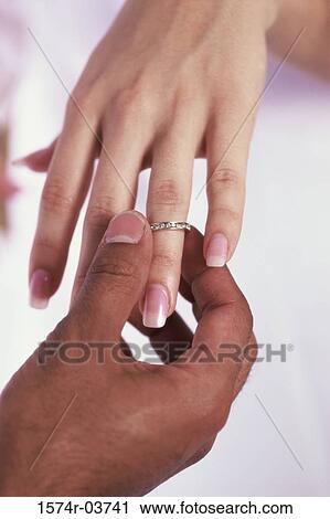 Man putting on a wedding ring on a woman's finger View Large Photo Image Stock Image - Man putting on a wedding ring on a woman's finger. Fotosearch