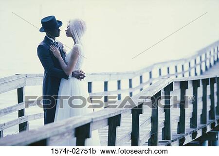 Newlywed couple embracing each other on a pier View Large Photo Image Stock Image - Newlywed couple embracing each other on a pier. Fotosearch