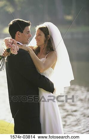 Picture - Newlywed couple embracing near a lake. Fotosearch