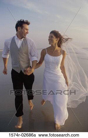Newlywed couple holding hands running on the beach View Large Photo Image Stock Image - Newlywed couple holding hands running on the beach. Fotosearch