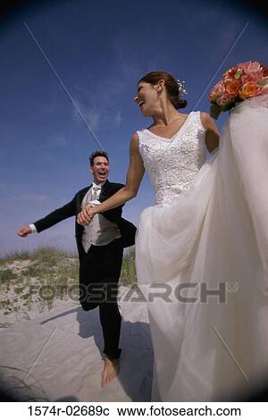 Newlywed couple running on sand View Large Photo Image Stock Image - Newlywed couple running on sand. Fotosearch