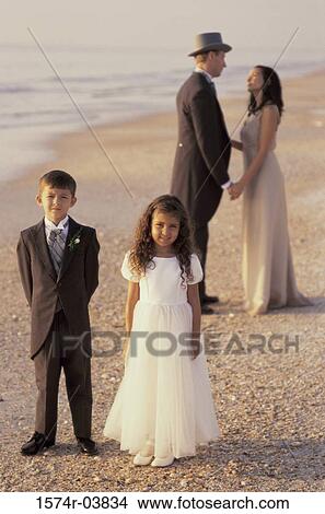 Picture - Newlywed couple standing on the beach with a flower girl and a ring bearer. Fotosearch
