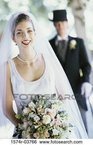 Stock Photograph - Portrait of a bride with her groom standing behind her. Fotosearch