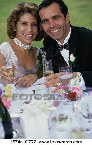 Stock Image - Portrait of a newlywed couple holding glasses of champagne. Fotosearch