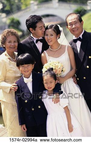 Stock Image - Portrait of a newlywed couple standing with their parents. Fotosearch
