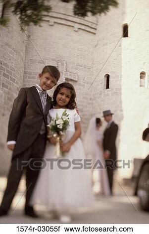 Stock Image - Portrait of a ring bearer and a flower girl standing in front of a church. Fotosearch