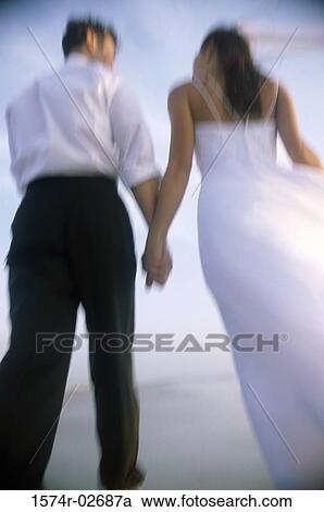 Rear view of a newlywed couple walking on the beach View Large Photo Image Stock Image - Rear view of a newlywed couple walking on the beach. Fotosearch