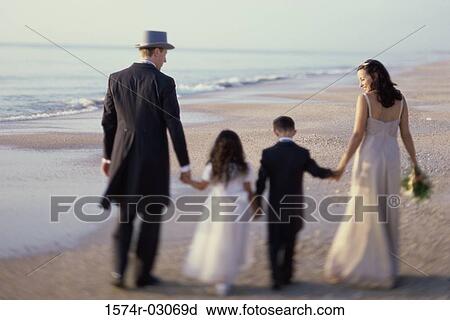 Rear view of a newlywed couple walking on the beach with a flower girl and a ring bearer View Large Photo Image Stock Image - Rear view of a newlywed couple walking on the beach with a flower girl and a ring bearer. Fotosearch