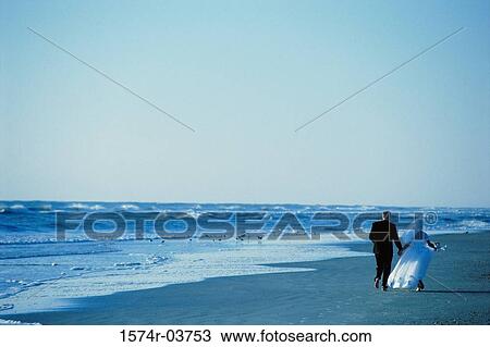 Rear view of a newlywed couple walking on the beach View Large Photo Image Stock Image - Rear view of a newlywed couple walking on the beach. Fotosearch