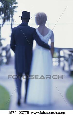 Rear view of a newlywed couple walking View Large Photo Image Stock Photograph - Rear view of a newlywed couple walking. Fotosearch