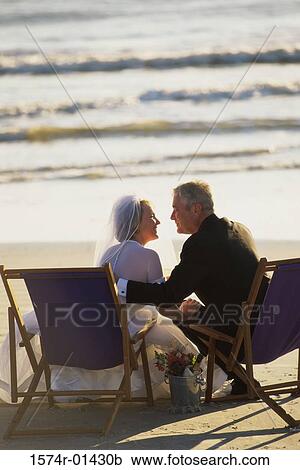 Senior couple sitting on deck chairs on the beach View Large Photo Image Stock Image - Senior couple sitting on deck chairs on the beach. Fotosearch