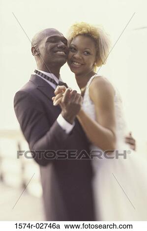 Stock Image - Side profile of a newlywed couple dancing. Fotosearch