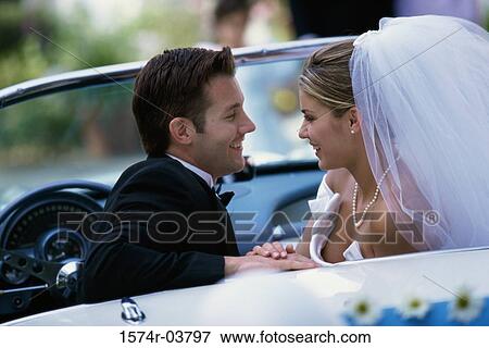 Side profile of a newlywed couple looking at each other in a convertible car View Large Photo Image Stock Photo - Side profile of a newlywed couple looking at each other in a convertible car. Fotosearch