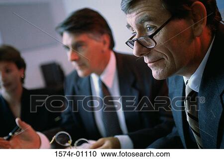 Business executives seated at a table in a meeting View Large Photo Image Stock Image - Business executives seated at a table in a meeting. Fotosearch