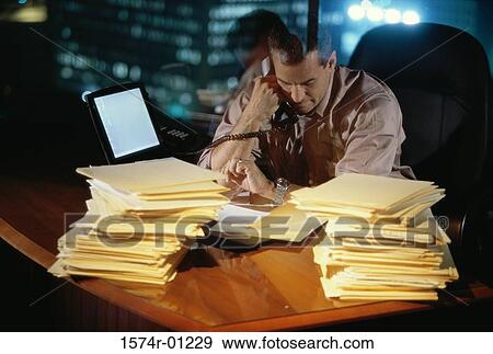 Stock Photo - Businessman checking time while talking on the landline telephone. Fotosearch