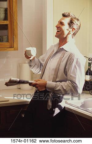 Businessman leaning against a counter holding a newspaper and a cup of coffee View Large Photo Image Stock Image - Businessman leaning against a counter holding a newspaper and a cup of coffee. Fotosearch