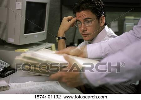 Stock Image - Businessman looking at a pile of papers in a person's hands. Fotosearch
