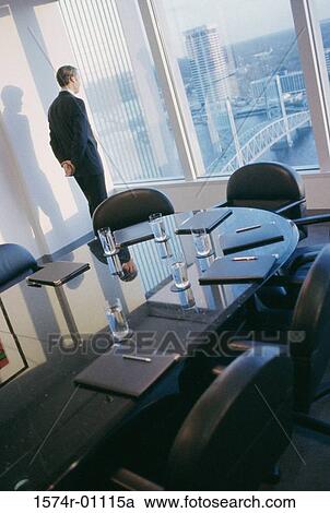 Stock Image - Businessman looking through a conference room window. Fotosearch