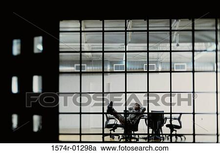 Stock Image - Businessman reclining in a conference room. Fotosearch