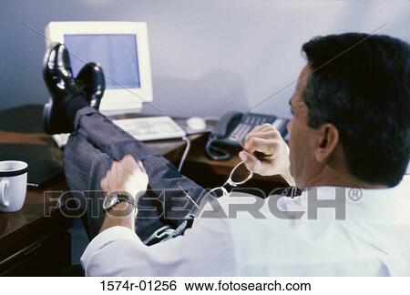 Stock Photograph - Businessman reclining in his seat with feet up on the table. Fotosearch
