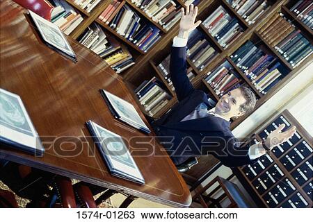 Businessman sitting in a library with arms raised View Large Photo Image Stock Image - Businessman sitting in a library with arms raised. Fotosearch
