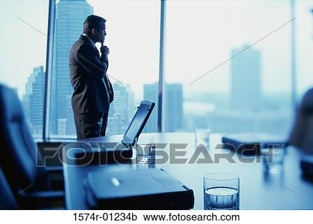 Stock Image - Businessman standing alone in a conference room. Fotosearch