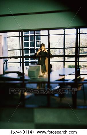Stock Photo - Businessman standing in his office talking on the landline telephone. Fotosearch