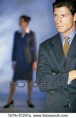 Businessman standing with a businesswoman in the background View Large Photo Image Stock Image - Businessman standing with a businesswoman in the background. Fotosearch