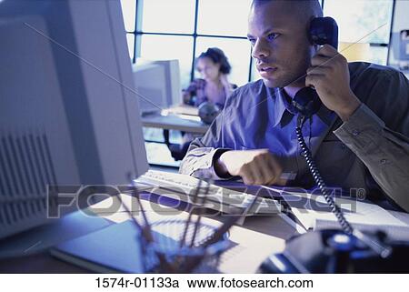 Stock Image - Businessman talking on a landline telephone. Fotosearch