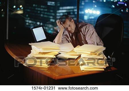 Stock Image - Businessman working on files at his desk. Fotosearch