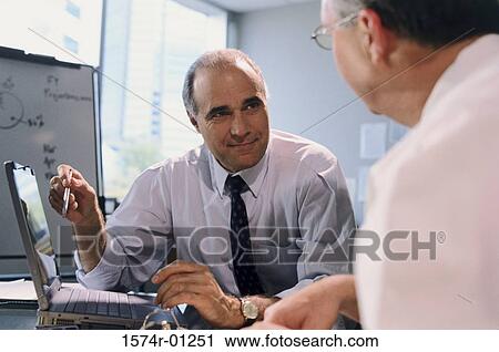 Stock Image - Businessmen discussing in an office. Fotosearch