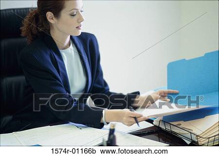 Businesswoman seated behind a desk in an office View Large Photo Image Stock Image - Businesswoman seated behind a desk in an office. Fotosearch