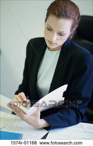 Stock Photo - Businesswoman seated behind a desk in an office. Fotosearch