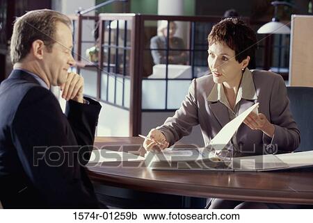 Stock Image - Businesswoman showing a businessman a file. Fotosearch
