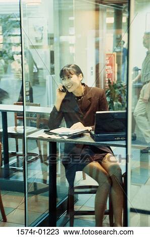 Stock Image - Businesswoman talking on a mobile phone in a cafe. Fotosearch
