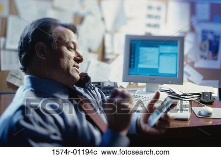 Stock Image - Close-up of a businessman talking on the landline telephone in the office. Fotosearch