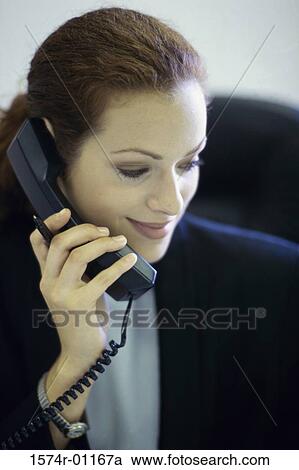 Stock Image - Close-up of a businesswoman talking on the landline telephone. Fotosearch