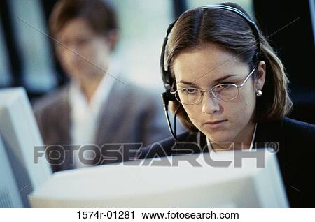 Stock Image - Close-up of a female customer service representative sitting in front of a computer monitor. Fotosearch
