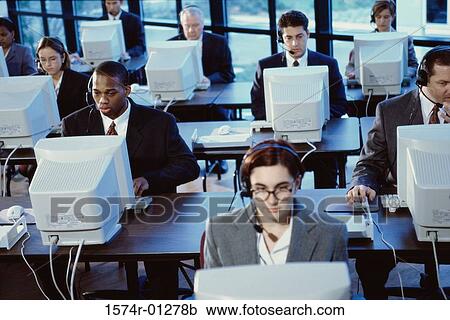 Stock Image - Customer service representatives sitting in front of computer monitors. Fotosearch