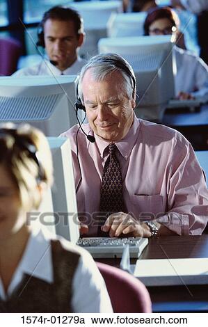 Stock Image - Customer service representatives sitting in front of computer monitors. Fotosearch