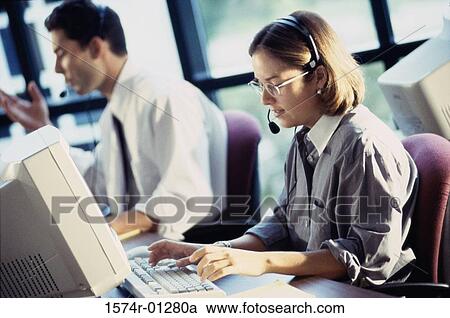Stock Image - Customer service representatives sitting in front of computer monitors. Fotosearch