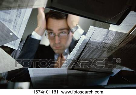 Low angle view of a businessman sitting at his desk holding his head View Large Photo Image Stock Image - Low angle view of a businessman sitting at his desk holding his head. Fotosearch