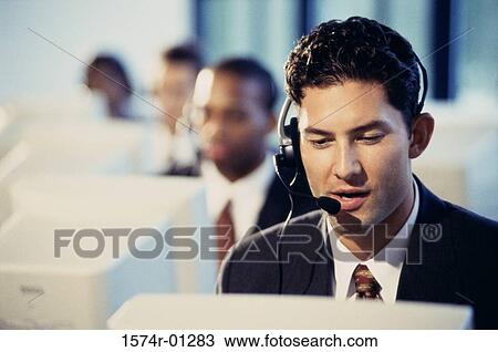 Stock Image - Male customer service representative sitting in front of a computer monitor. Fotosearch