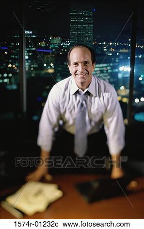 Stock Image - Portrait of a businessman standing at his desk. Fotosearch