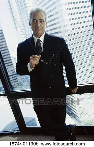Portrait of a businessman standing against a window View Large Photo Image Stock Image - Portrait of a businessman standing against a window. Fotosearch