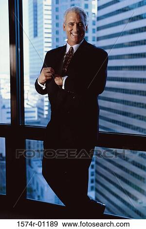 Stock Photo - Portrait of a businessman standing against a window. Fotosearch
