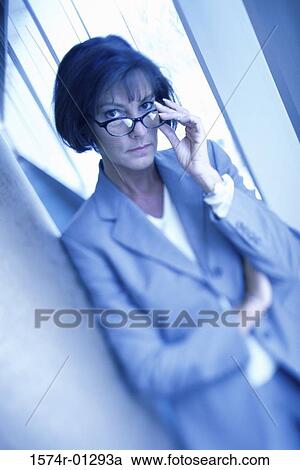 Stock Image - Portrait of a businesswoman holding her eyeglasses. Fotosearch