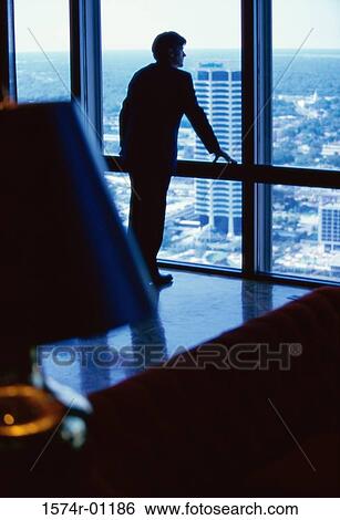 Rear view of a businessman standing at a window View Large Photo Image Stock Photograph - Rear view of a businessman standing at a window. Fotosearch