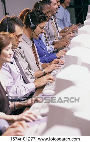 Row of customer service representatives sitting in front of computer monitors View Large Photo Image Stock Photo - Row of customer service representatives sitting in front of computer monitors. Fotosearch